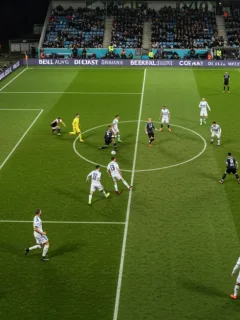 Football players contesting a corner kick in a packed stadium during a European match.