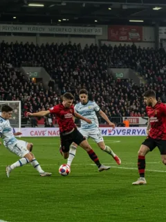 Dynamic football player delivering a creative assist in a European match, stadium lights illuminating the field.
